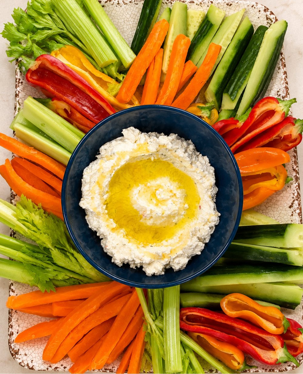 Crudité arranged in a radial pattern around a bowl of whipped feta with olive oil