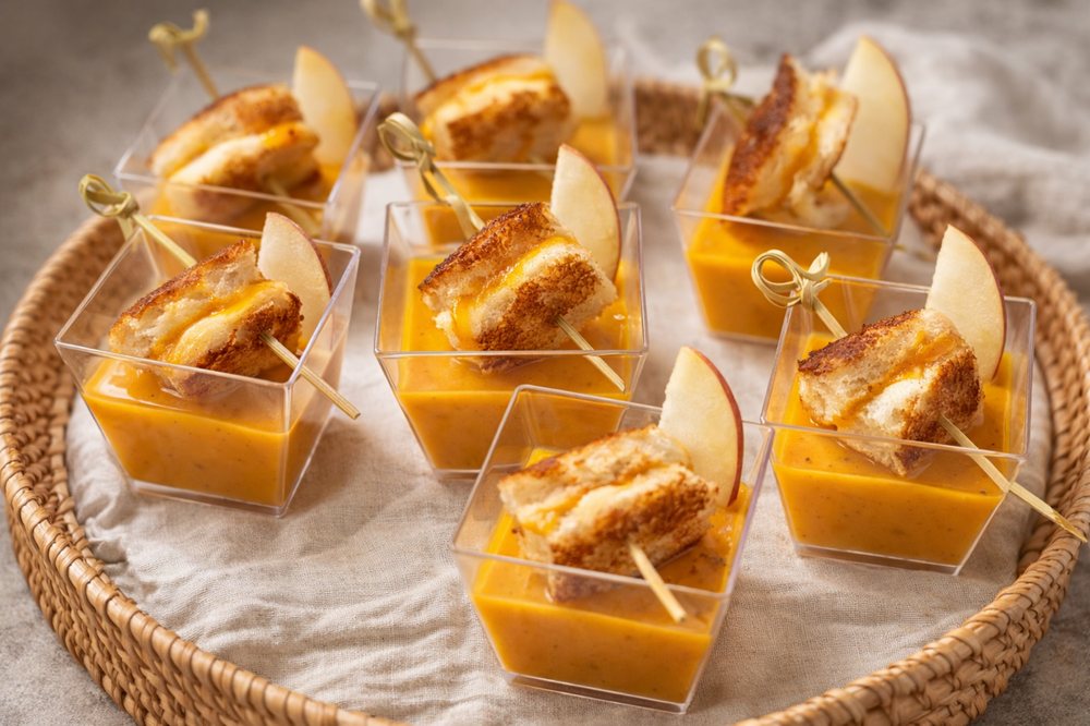 Individual glasses of butternut squash bisque with grilled cheese skewers and apple